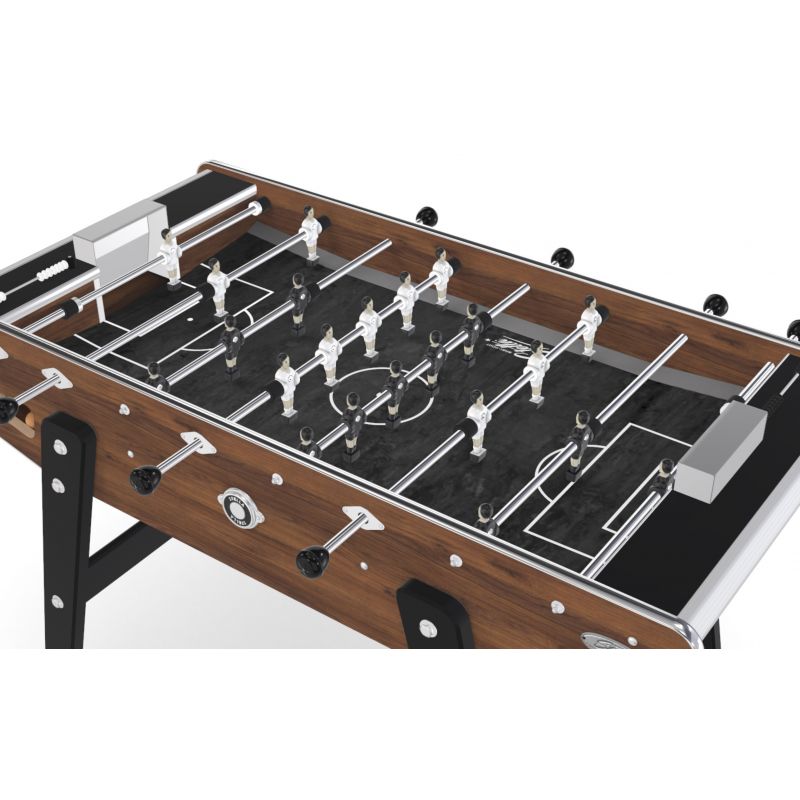 Gros plan sur la caisse effet noyer du baby-foot Stella Home Warmia avec sortie de balle et pieds noirs.