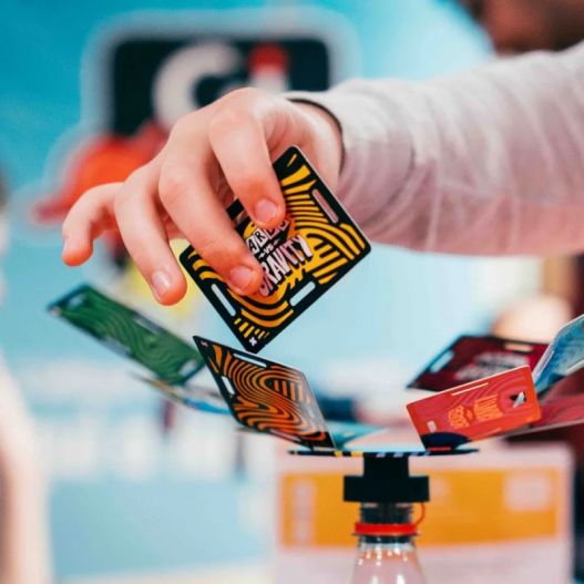 Main d’un joueur plaçant une carte sur la structure en équilibre du jeu Instable.