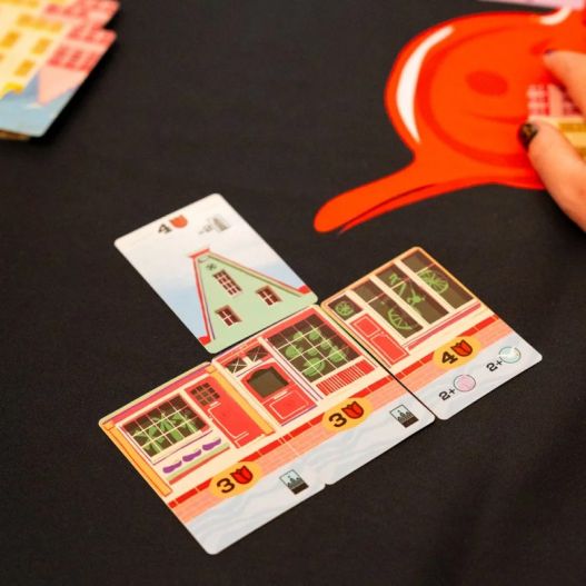 Exemple de bâtiment en construction dans le jeu Bellevue avec cartes alignées sur une table.