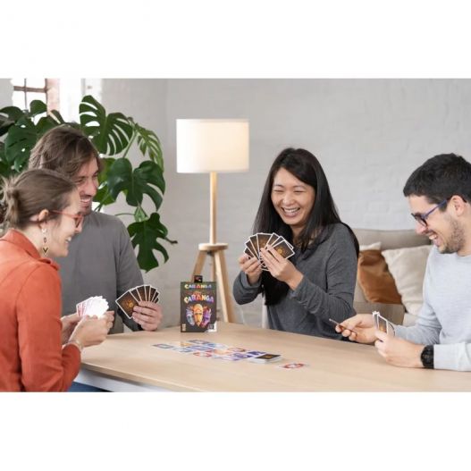 Scène conviviale où des joueurs rient tout en jouant à Cabanga à une table.