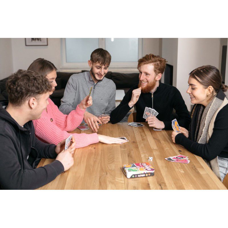 Cinq amis autour d'une table en train de jouer à Papayoo, tous souriants et concentrés sur leurs cartes.