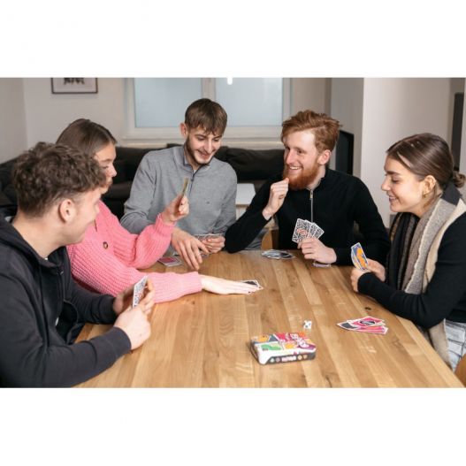 Cinq amis autour d'une table en train de jouer à Papayoo, tous souriants et concentrés sur leurs cartes.