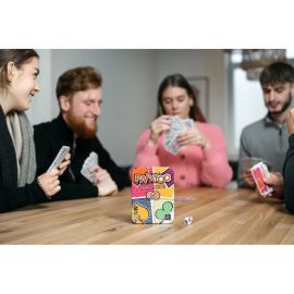 Boîte du jeu Papayoo placée au centre d’une table pendant une partie avec des joueurs en arrière-plan et un dé posé à côté.