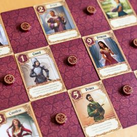 Partie en cours de Love Letter avec cartes disposées sur la table et jetons posés sur les cartes.