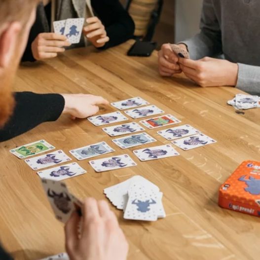 Zoom sur les cartes posées au centre d'une table avec des joueurs en pleine partie de 6 qui prend !