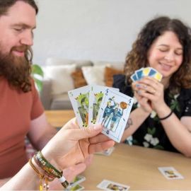 Joueur tenant des cartes du jeu Rebelles Princesses pendant une partie conviviale.