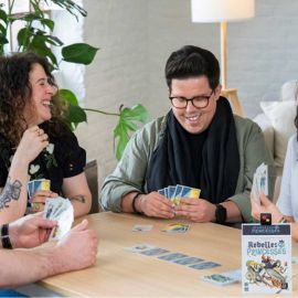Groupe d'adultes jouant au jeu Rebelles Princesses autour d'une table, ambiance joyeuse.