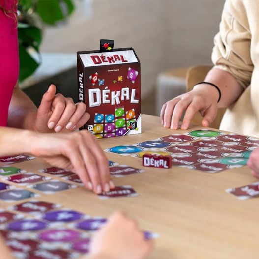 Gros plan sur les mains des joueurs manipulant les cartes du jeu DÉKAL.