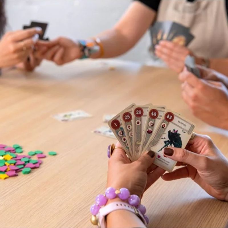 Partie en cours du jeu Once Upon a Draft, des joueurs tiennent des cartes en main et utilisent des jetons colorés.