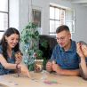 Groupe de quatre personnes concentrées et souriantes jouant à Once Upon a Draft, boîte du jeu visible au centre de la table.