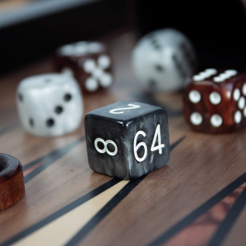 Dé à l'effet marbré posé sur le plateau de backgammon, entouré d'autres dés