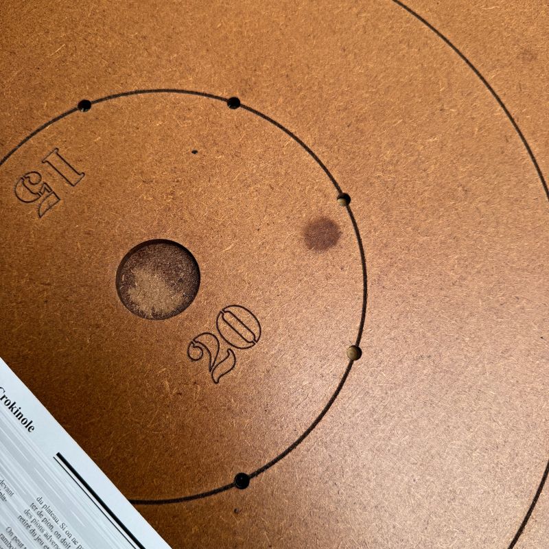 gros plan sur la zone centrale gravée d'un plateau de crokinole, avec les valeurs de points