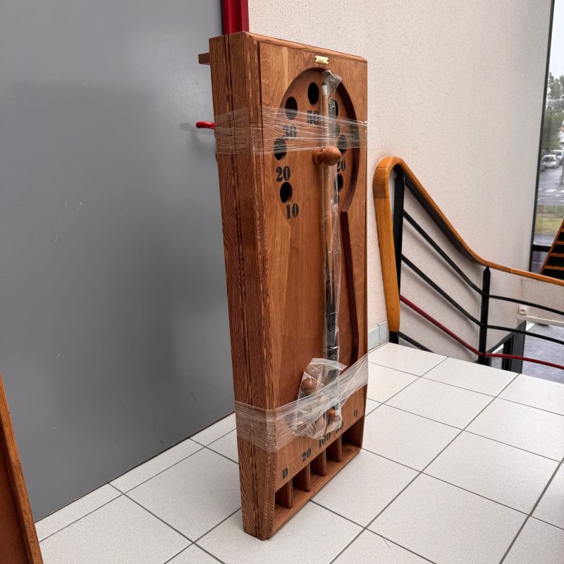 Sachet de billes en bois posé au pied du plateau du billard carrousel