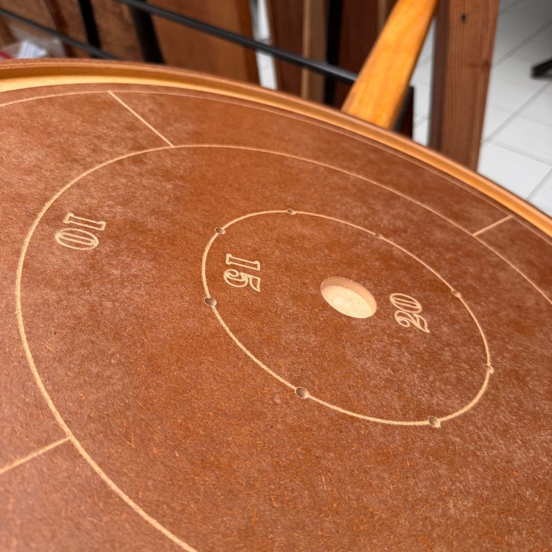 Trou central et zones numérotées 10, 15 et 20 sur un plateau de crokinole