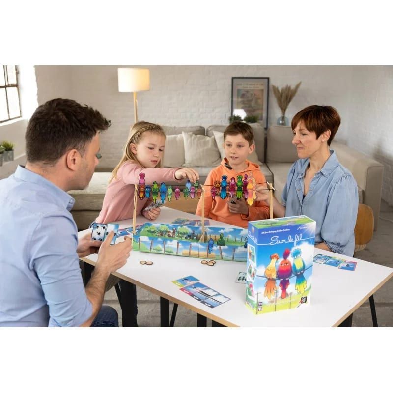 Famille jouant à Sur le fil autour d'une table, boîte du jeu posée à côté