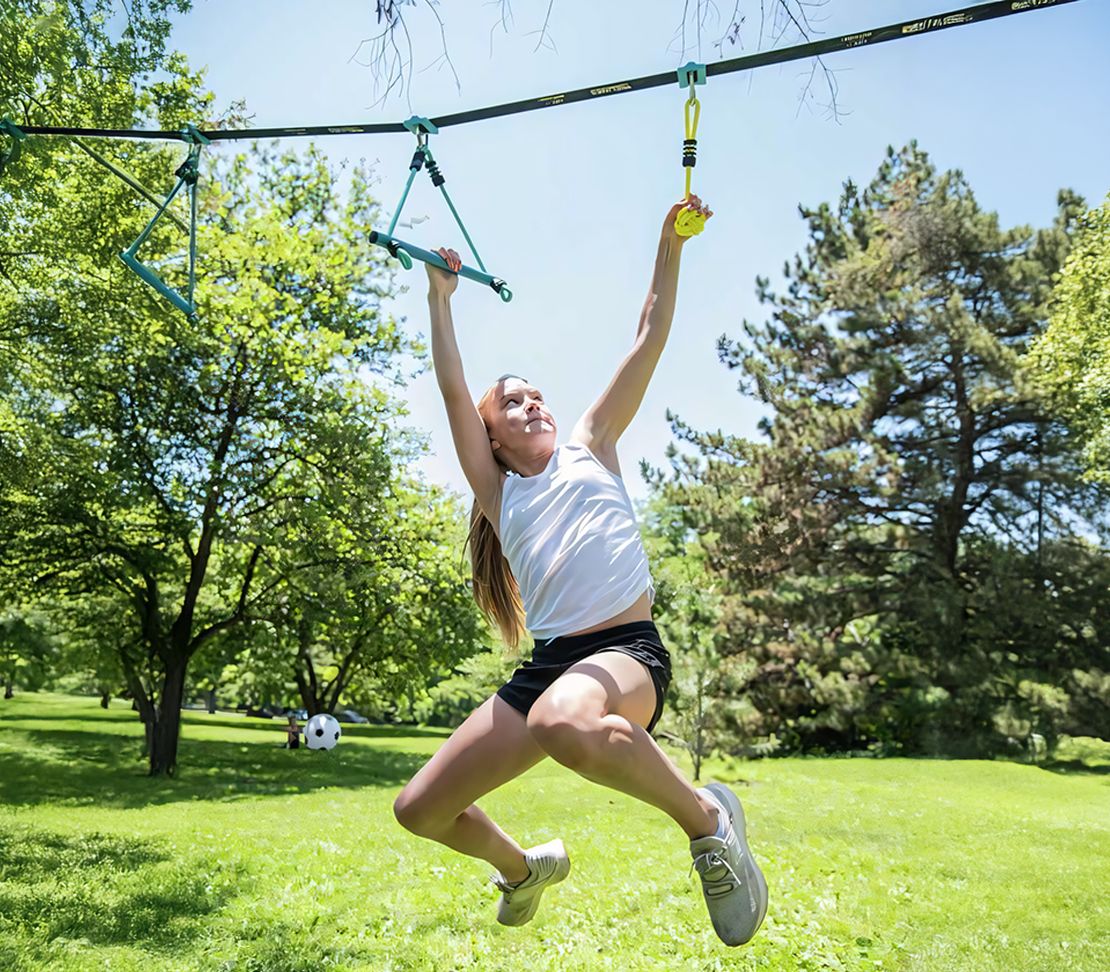 Jeune femme utilisant les obstacles suspendus du kit Ninja Adventure Trelines au parc.